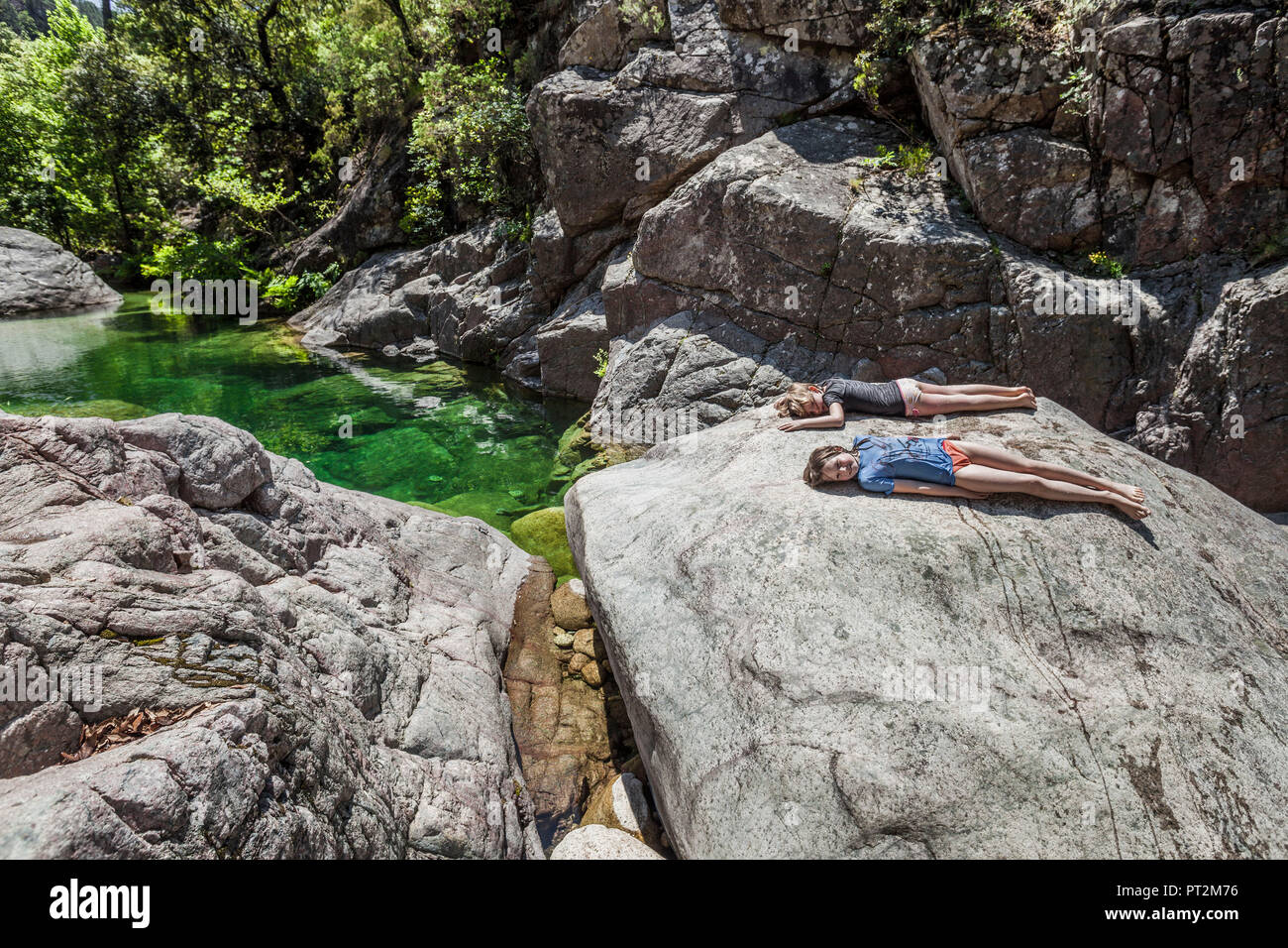 2 Mädchen auf einem Felsen in einer bizarren Landschaft vor tiefen grünen Wasser Stockfoto