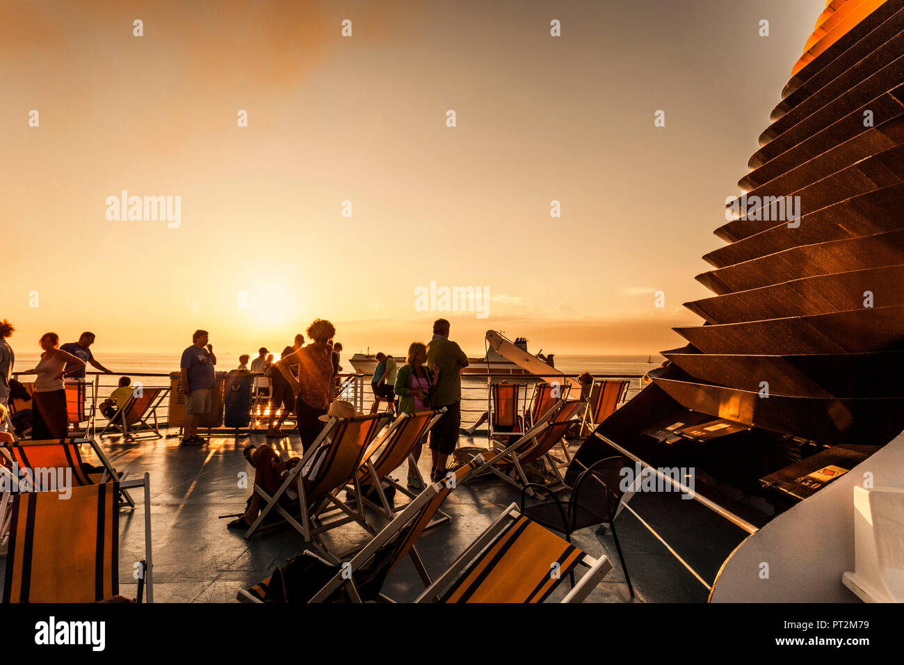 Passagiere an Deck eines Schiffes mit Blick auf die Abendsonne Stockfoto