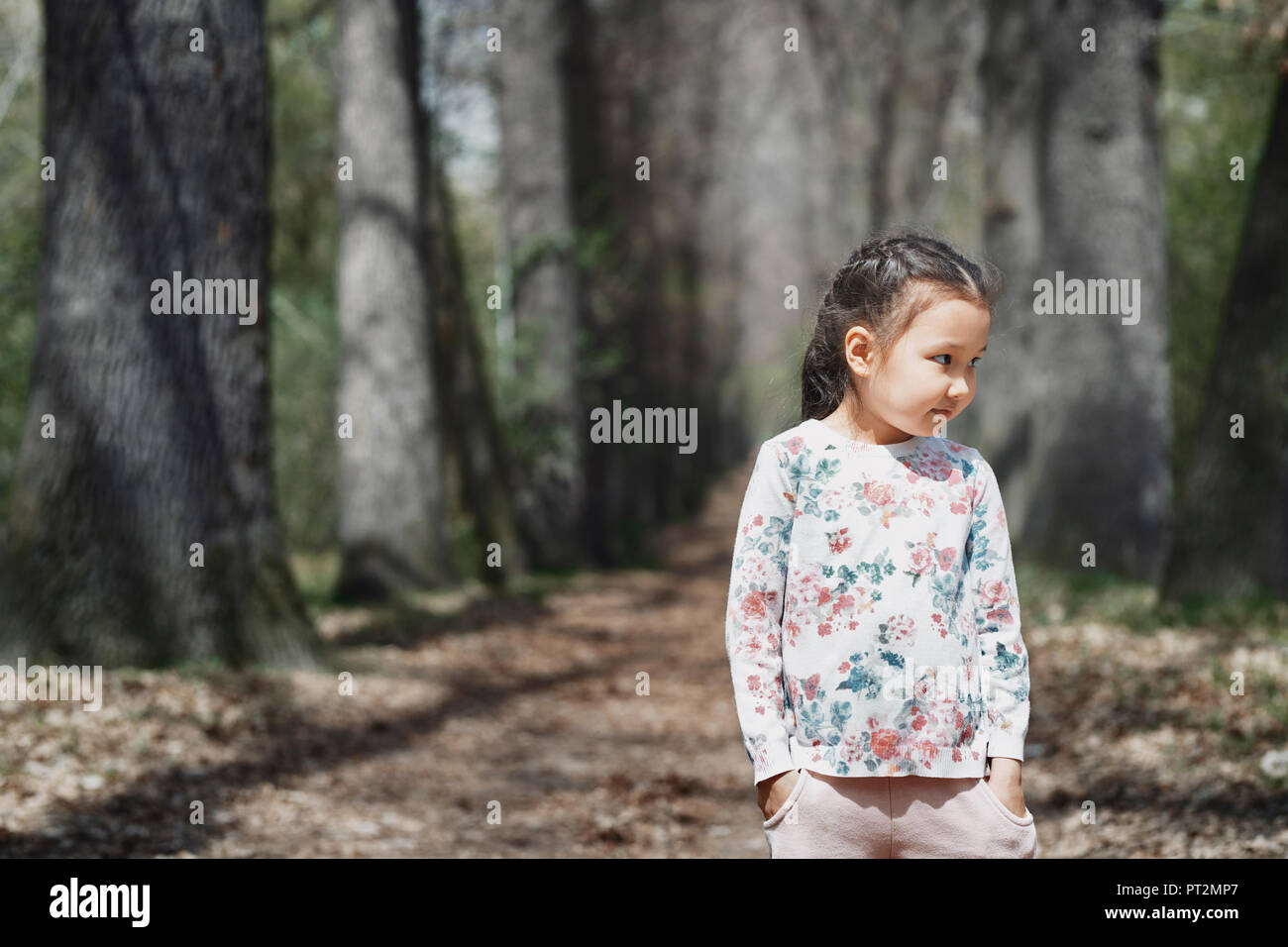 Littele stehendes Mädchen im Park, mit den Händen in den Taschen Stockfoto