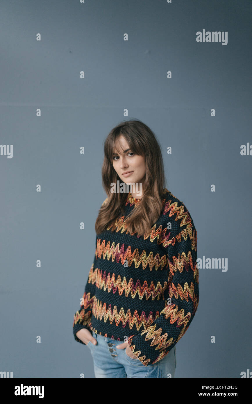 Pretty Woman gegen grauen Hintergrund, mit den Händen in den Taschen Stockfoto