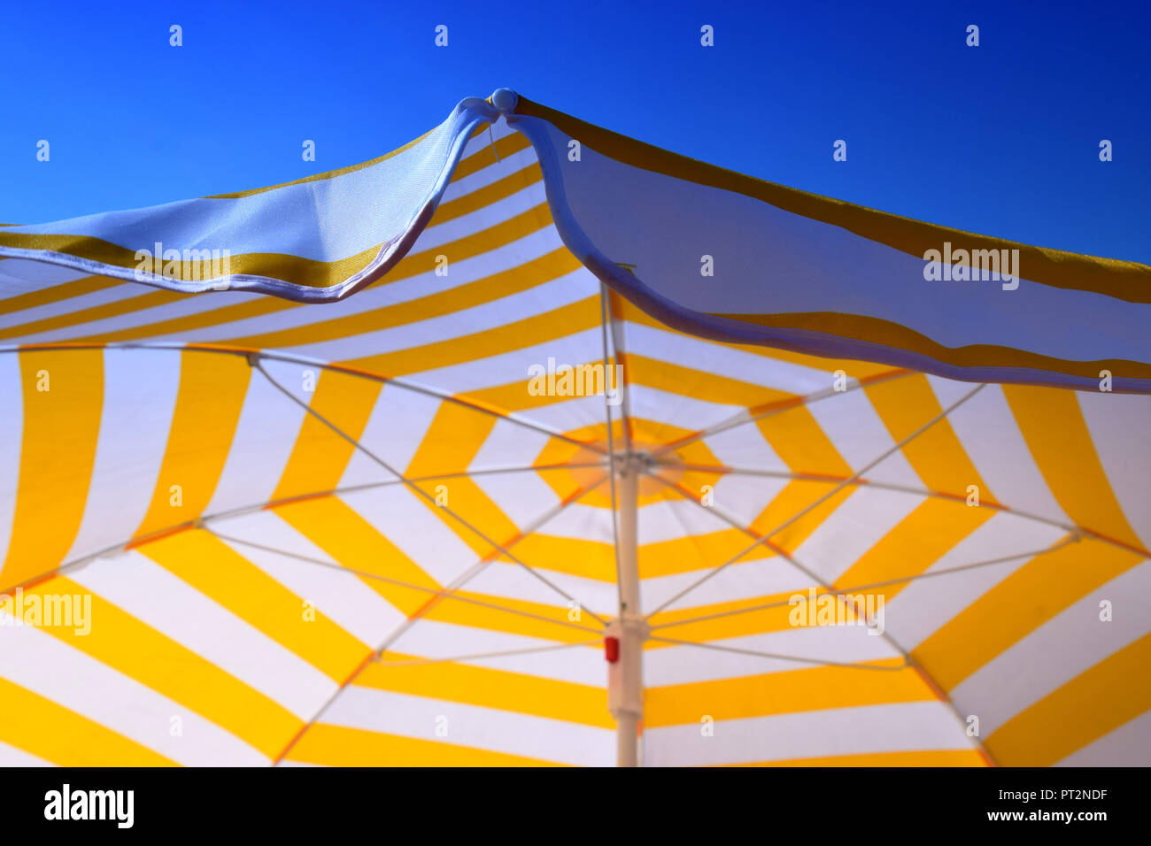 Big weiß und gelb gestreifte Schirm und klaren Sommer Himmel, gelb-weiß  gestreifte Sonnenschirm vor dem azurblauen Himmel als Symbol für  Ferienhäuser Stockfotografie - Alamy