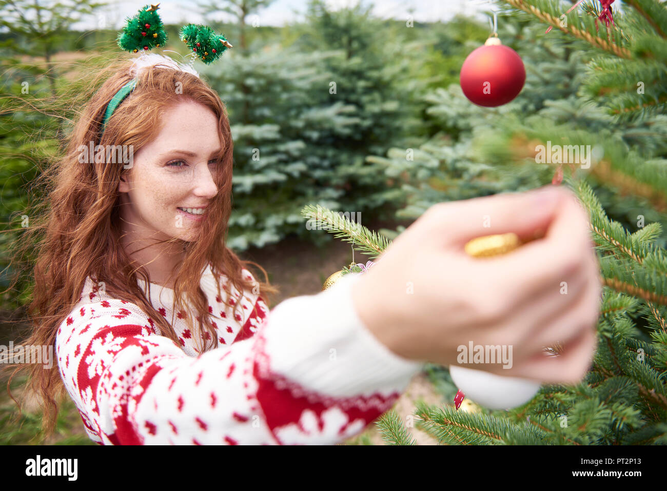 Rothaarige junge Frau schmücken Weihnachtsbaum im Freien Stockfoto