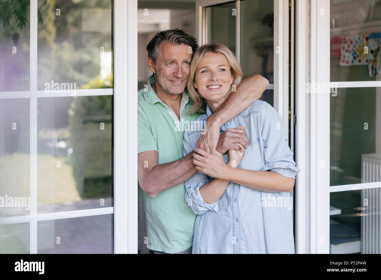 Gerne reifes Paar umarmen an französische Fenster Stockfoto