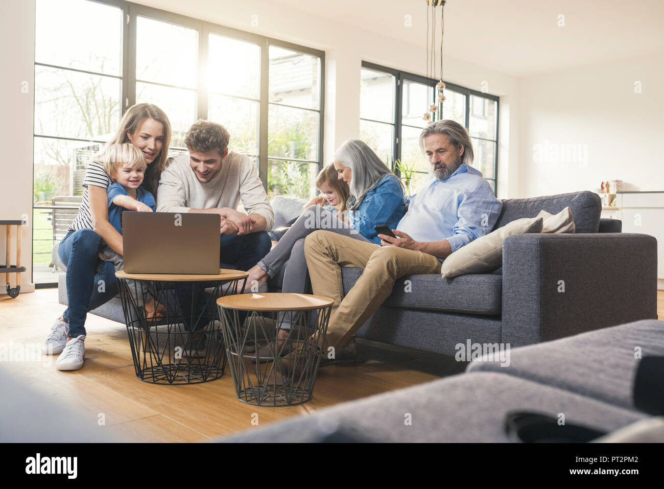 Erweiterte Familie sitzt auf der Couch, mit mobilen Geräten Stockfoto