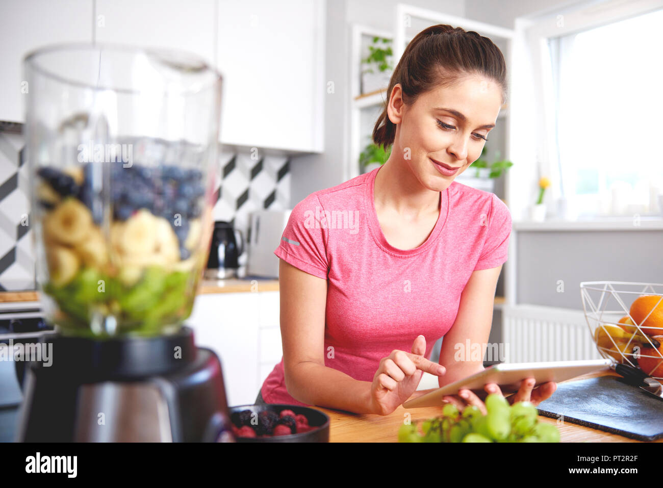 Portrait von lächelnden jungen Frau mit Tablet in der Küche Stockfoto