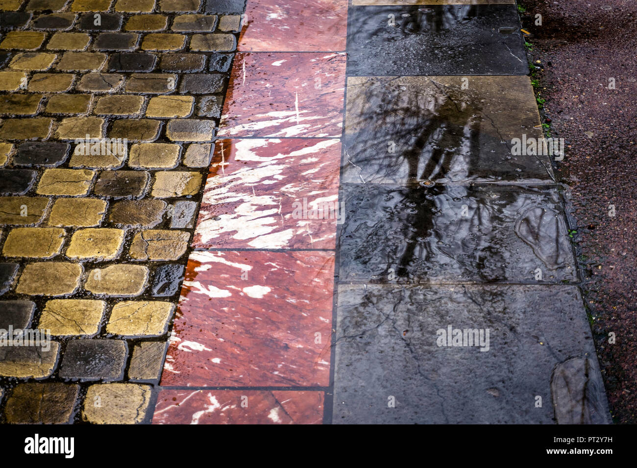 Bürgersteig in Narbonne, verschiedene Pflastersteine, Reflexionen im Wasser in der Regen Stockfoto