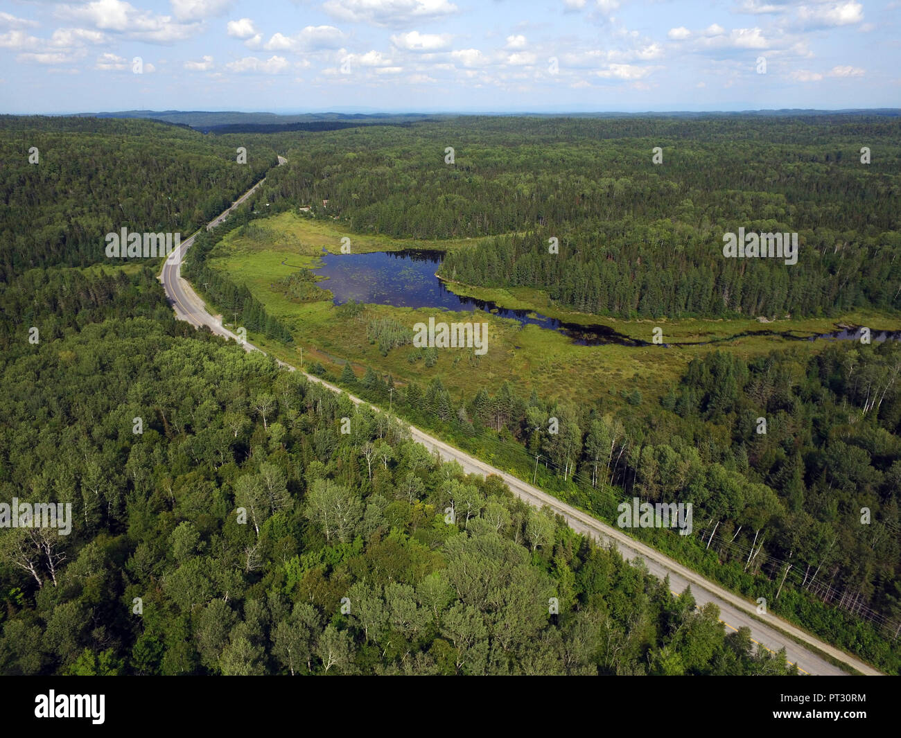 Luftaufnahme von eine Straße durch den Wald und Berge mit Moor oder Sumpf, Quebec, Kanada Stockfoto