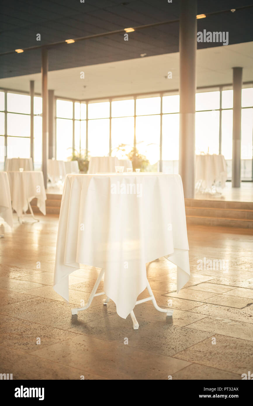 Interieur mit poseur Tabellen, weißen Tischdecken und warmes Sonnenlicht Stockfoto