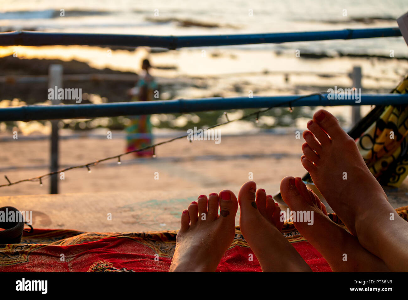 Zwei Paare von Frauen Füße sehen, ein Sandstrand, wie die Sonne einen goldenen Glanz. Stockfoto
