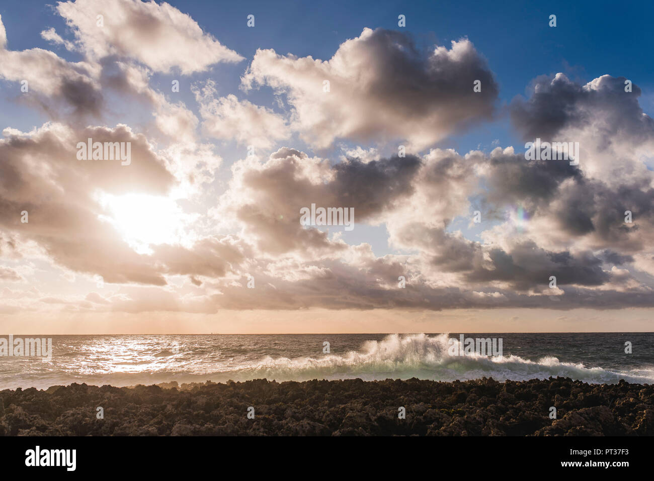 Felsiger Strand mit Welle brechen, Sonne und Wolken spielen, Winter in Griechenland Stockfoto