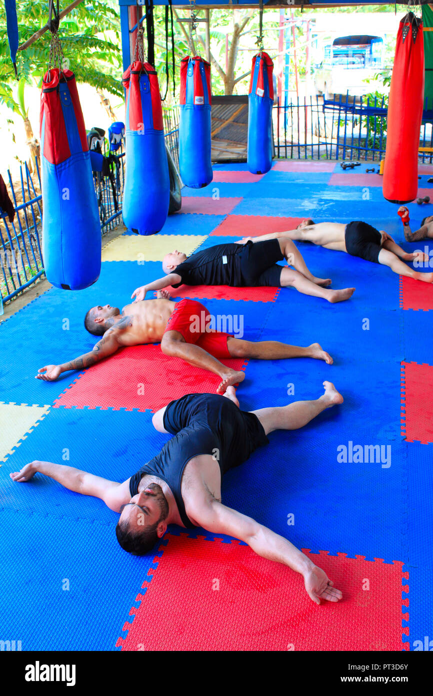 PHETCHABUN, THAILAND, Mai 2018, Männer tun Torso twist stretch auf dem Boden liegend in einem geöffneten Fitnessraum bei Ban Bung Sam Phan Nok. Stockfoto