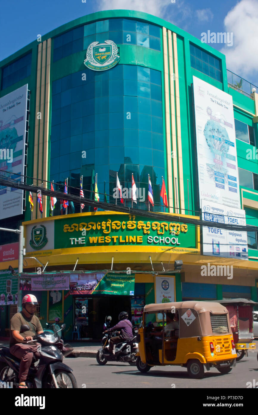 Verkehr passieren Die westline Schule, ein Englisch, Chinesisch, und Khmer Sprache Institution, auf einer Straße der Stadt in Phnom Penh, Kambodscha. Stockfoto