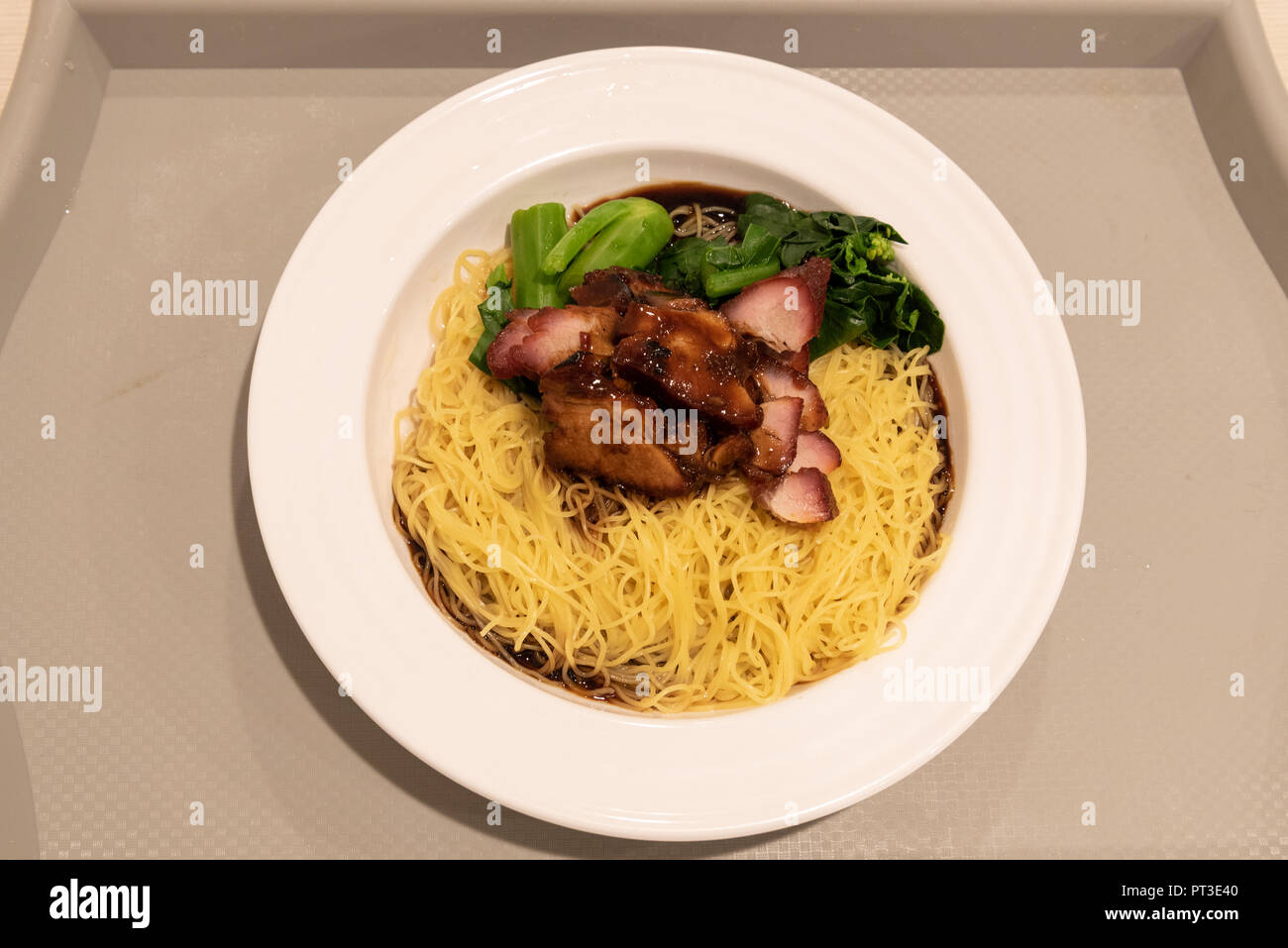 Ein Teller mit BBQ-Schweinefleischnudeln auf einem Tablett. Char Siew-Nudeln. Essen aus Singapur. Stockfoto