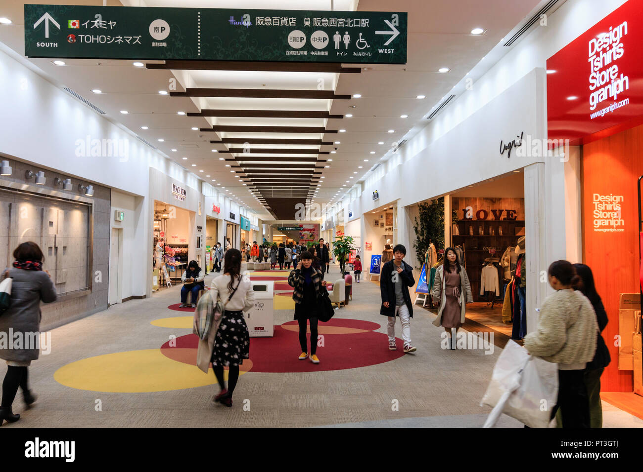 Innenraum der Nishinomiya Gärten Shopping Center, Japan. Käufer entlang Teppichboden shopping Gang mit Geschäften auf beiden Seiten. Stockfoto