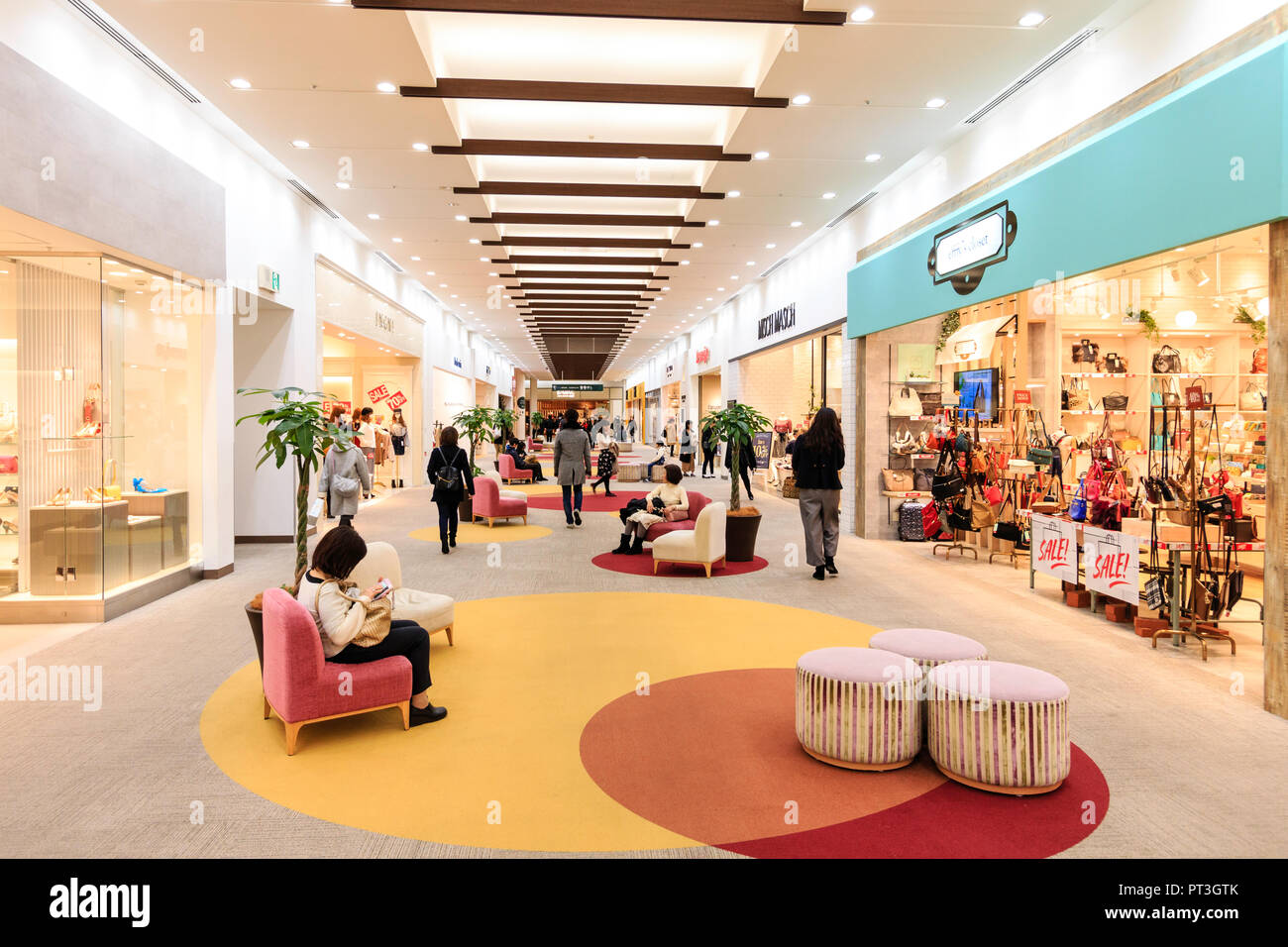 Innenraum der Nishinomiya Gärten Shopping Center, Japan. Käufer einige sitzen und einige entlang Teppichboden shopping Gang mit Geschäften auf beiden Seiten Stockfoto