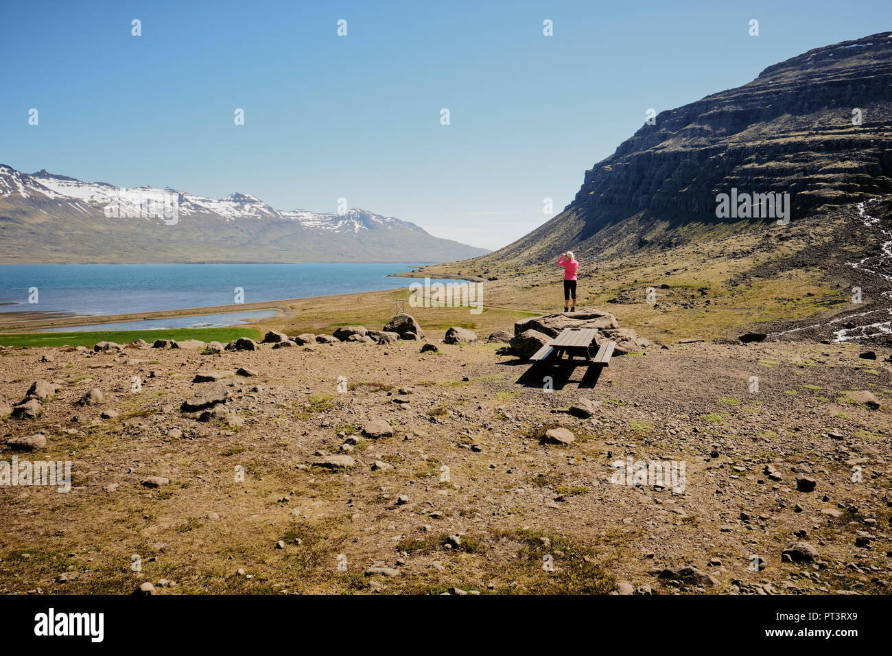 Ein einsamer Tourist in Rosa, die in der zerklüfteten Landschaft der Fjorde Region im Osten von Island. Stockfoto