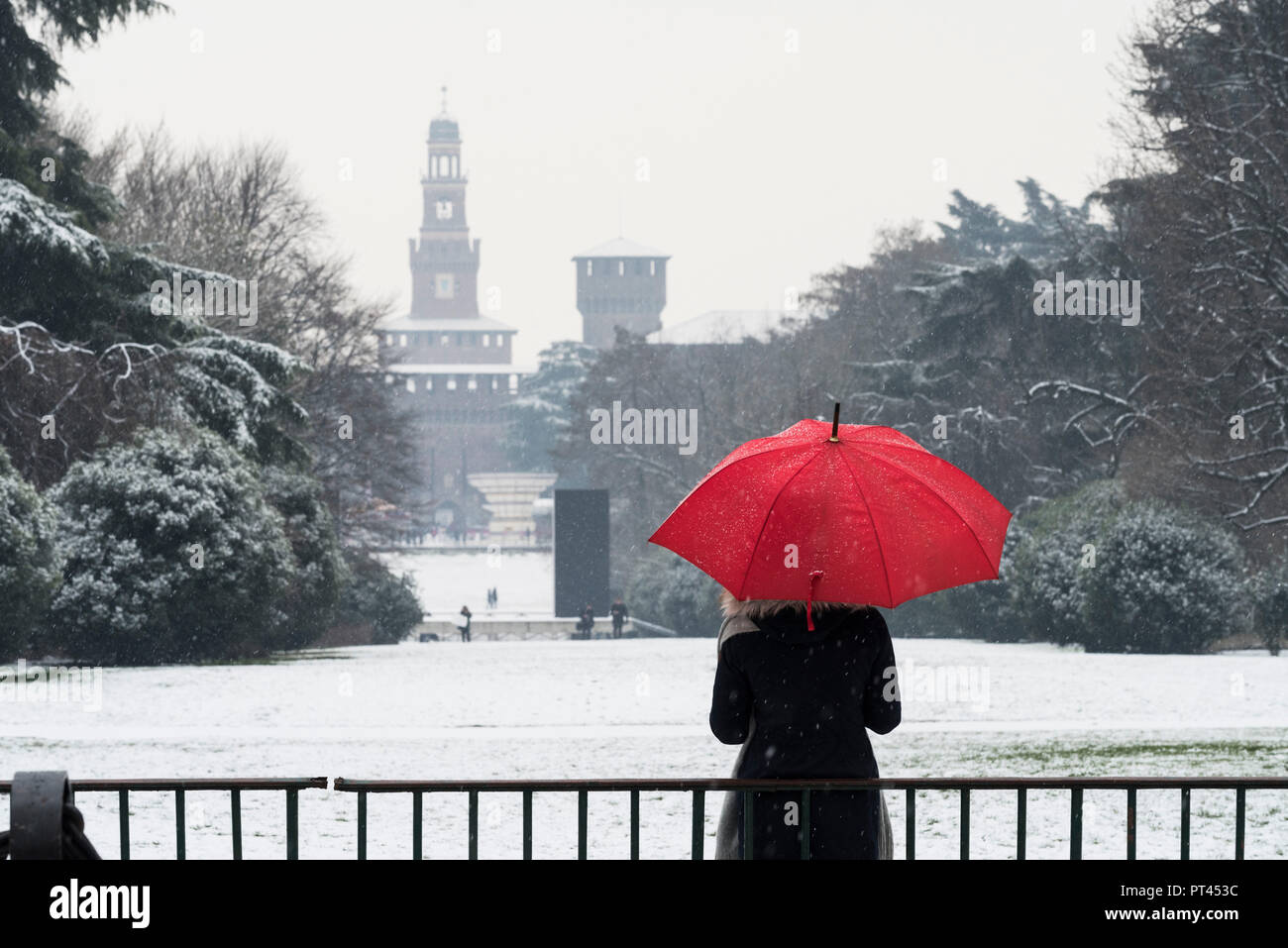 Eine Frau mit roten Regenschirm bewundert die Ansicht des Sempione Park während einer Schneefall, Mailand, Lombardei, Italien, Europa, Stockfoto