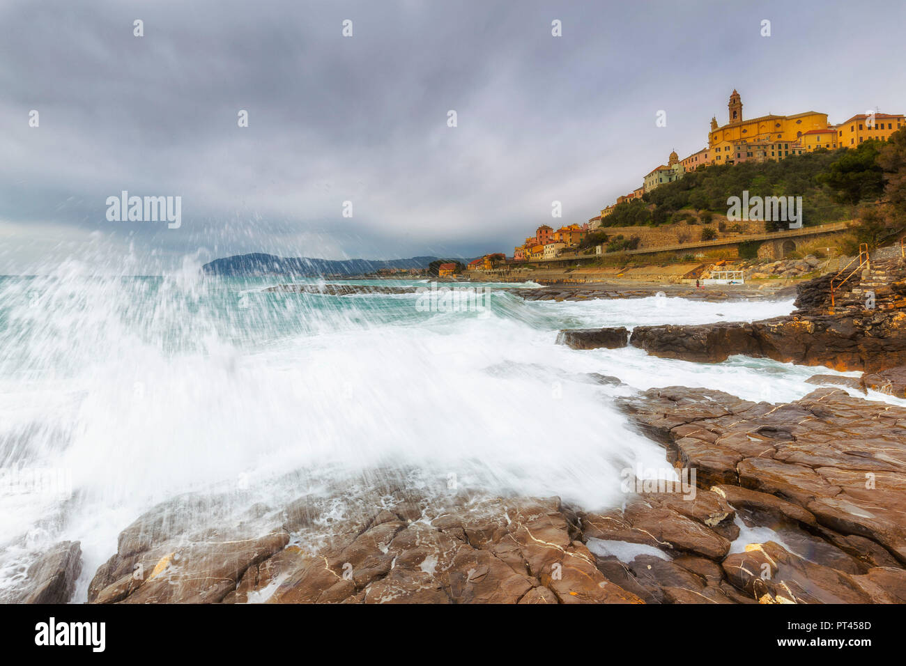 Wellen auf den Felsen mit dem Dorf Cervo im Hintergrund, Cervo, Provinz Imperia, Ligurien, Italien, Europa, Stockfoto