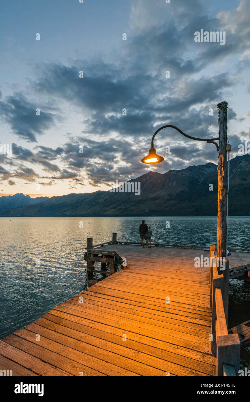 Mann und Kind auf dem Steg bei Dämmerung, Glenorchy, Queenstown, Lake District, Region Otago, Südinsel, Neuseeland, Stockfoto