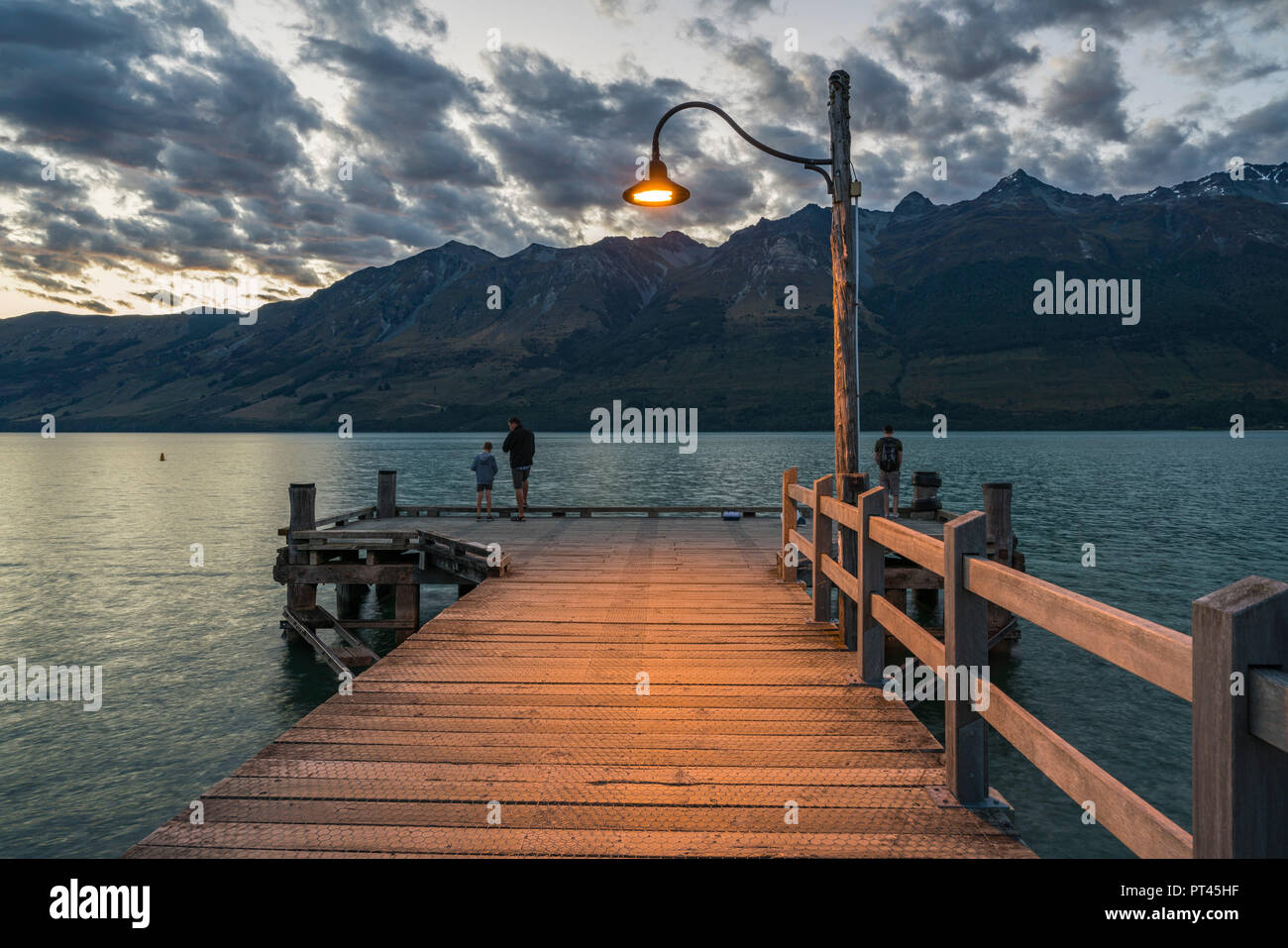 Drei Menschen auf dem Steg bei Dämmerung, Glenorchy, Queenstown, Lake District, Region Otago, Südinsel, Neuseeland, Stockfoto