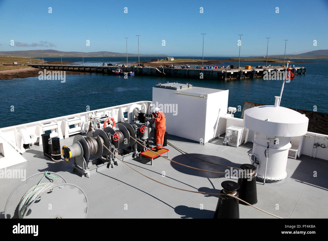 Ein Mitglied der Decksmannschaft wiegen Anker auf dem hinteren Deck der Fähre Hamnavoe, Stromness Hafen, Orkney, Schottland Stockfoto