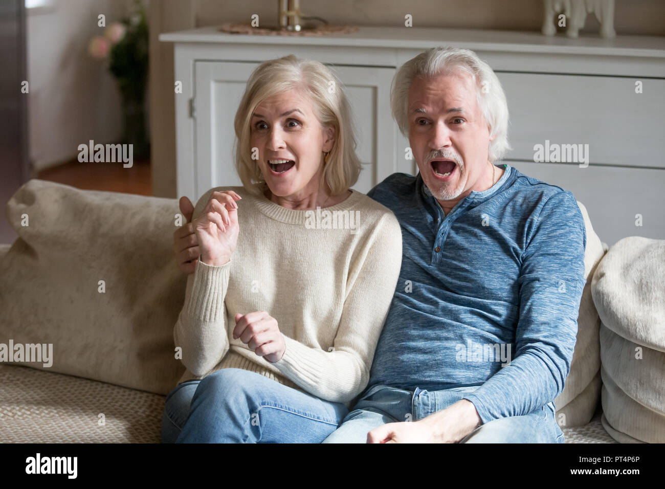 Überrascht senior Paar mittleren Alters Zuschauer erstaunt Gefühl gerade neue Reality-Show im Fernsehen, erstaunt, alte Reifen Familie looki schockiert Stockfoto