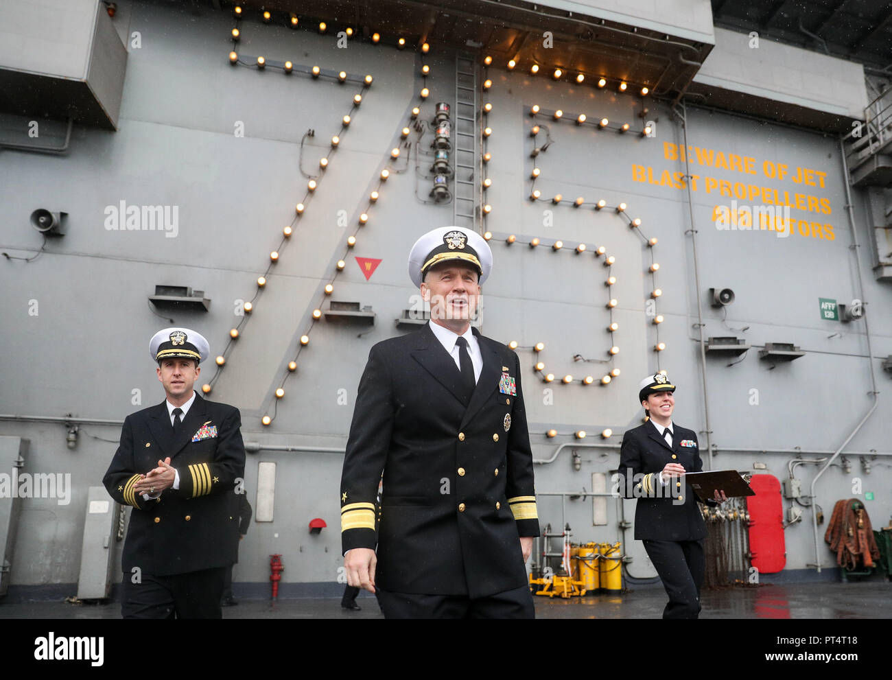 Der Rückadmiral Eugene H. 'Gene' Black, Commander, Carrier Strike Group 8 (Mitte), und Kapitän Nichola J. Denna, Kommandant (links), auf dem Flugdeck des US-amerikanischen Flugzeugträgers USS Harry S. Truman, der während eines Besuchs in Portsmouth in Stokes Bay, Hampshire, eintrifft. Stockfoto