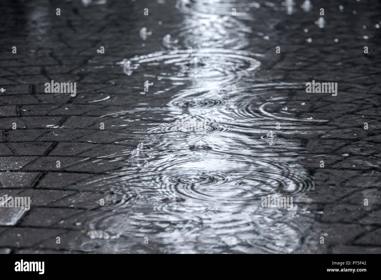 Überflutete Straße Gehweg mit gewellter regen Wasserpfützen Stockfoto