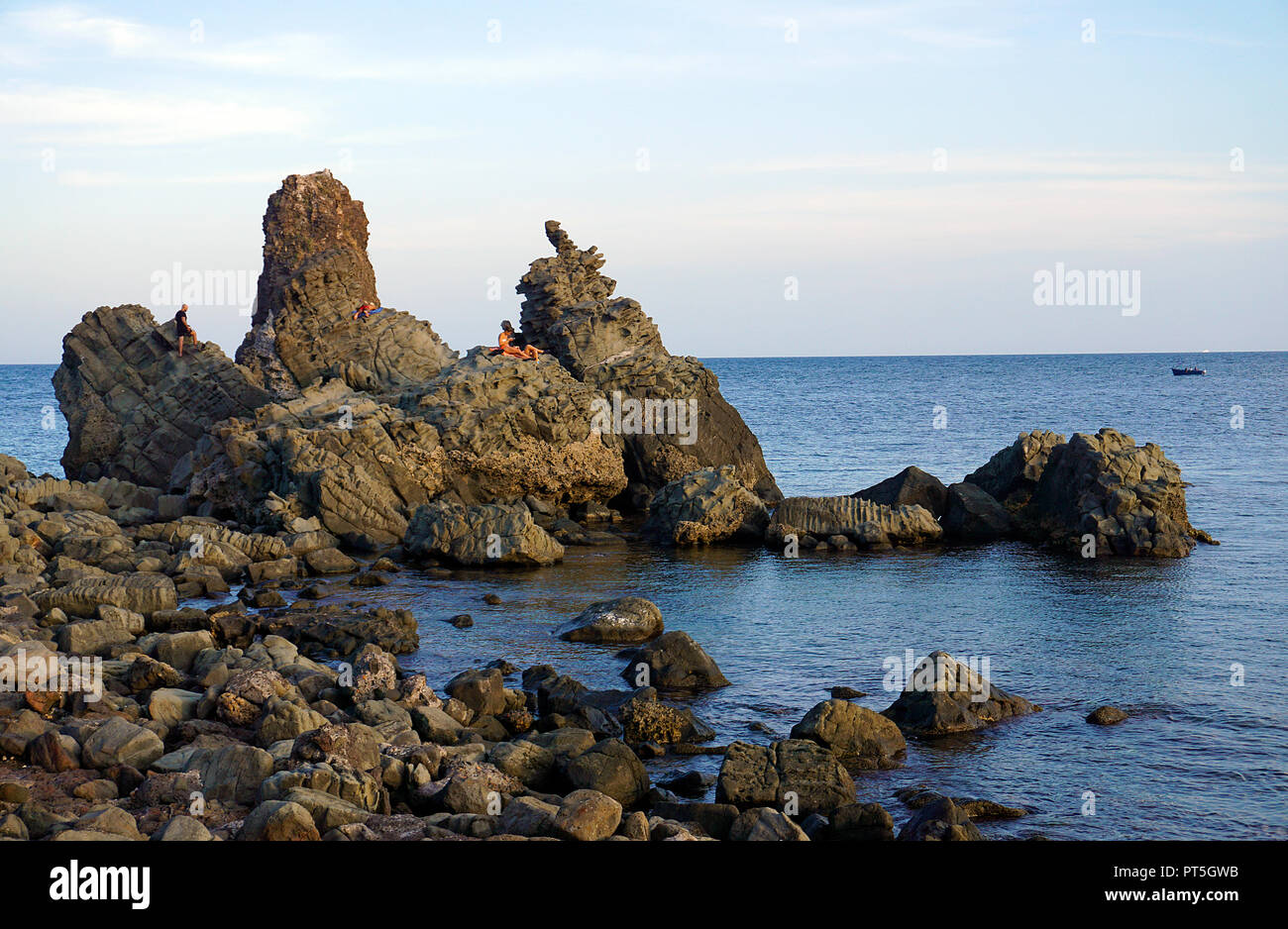Leute auf einem Basaltfelsen am Cyclops Inseln, Aci Trezza, Gemeinde Aci Castello, Catania, Sizilien, Italien Stockfoto