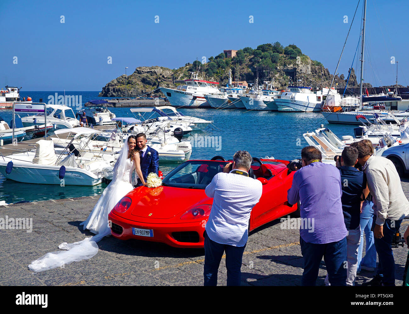 Foto Session, Brautpaar mit Ferrari am Hafen von Aci Trezza, hinter der Insel Lachea, Hauptinsel der Zyklopen, Catania, Sizilien, Italien Stockfoto