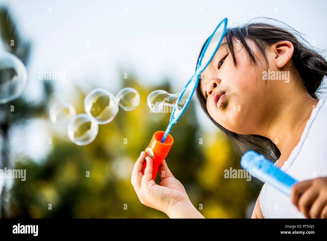Mädchen bläst Seifenblasen mit Bubble Wand im Park. Stockfoto