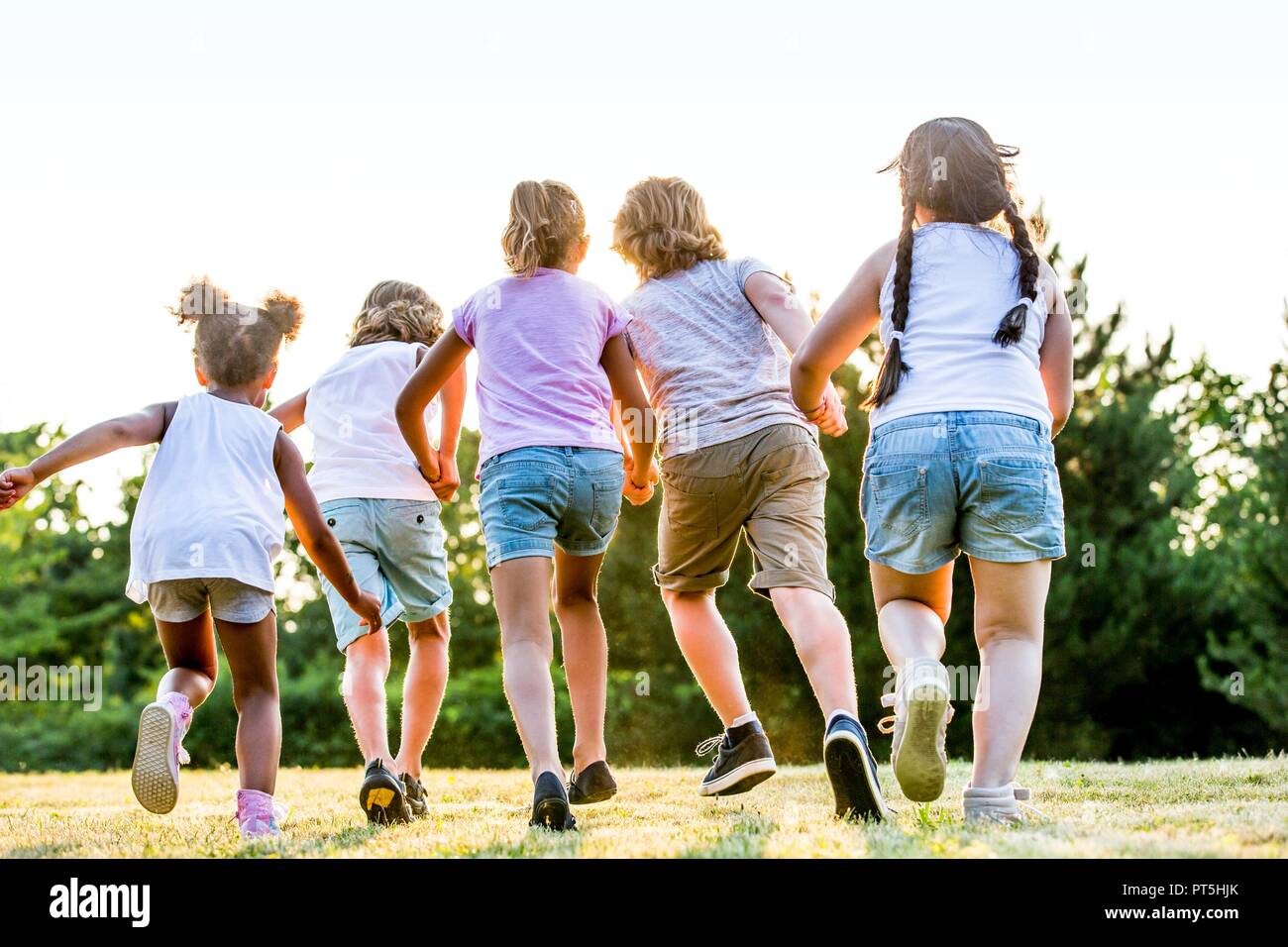 Kinder halten sich an den Händen und Laufen im Park. Stockfoto