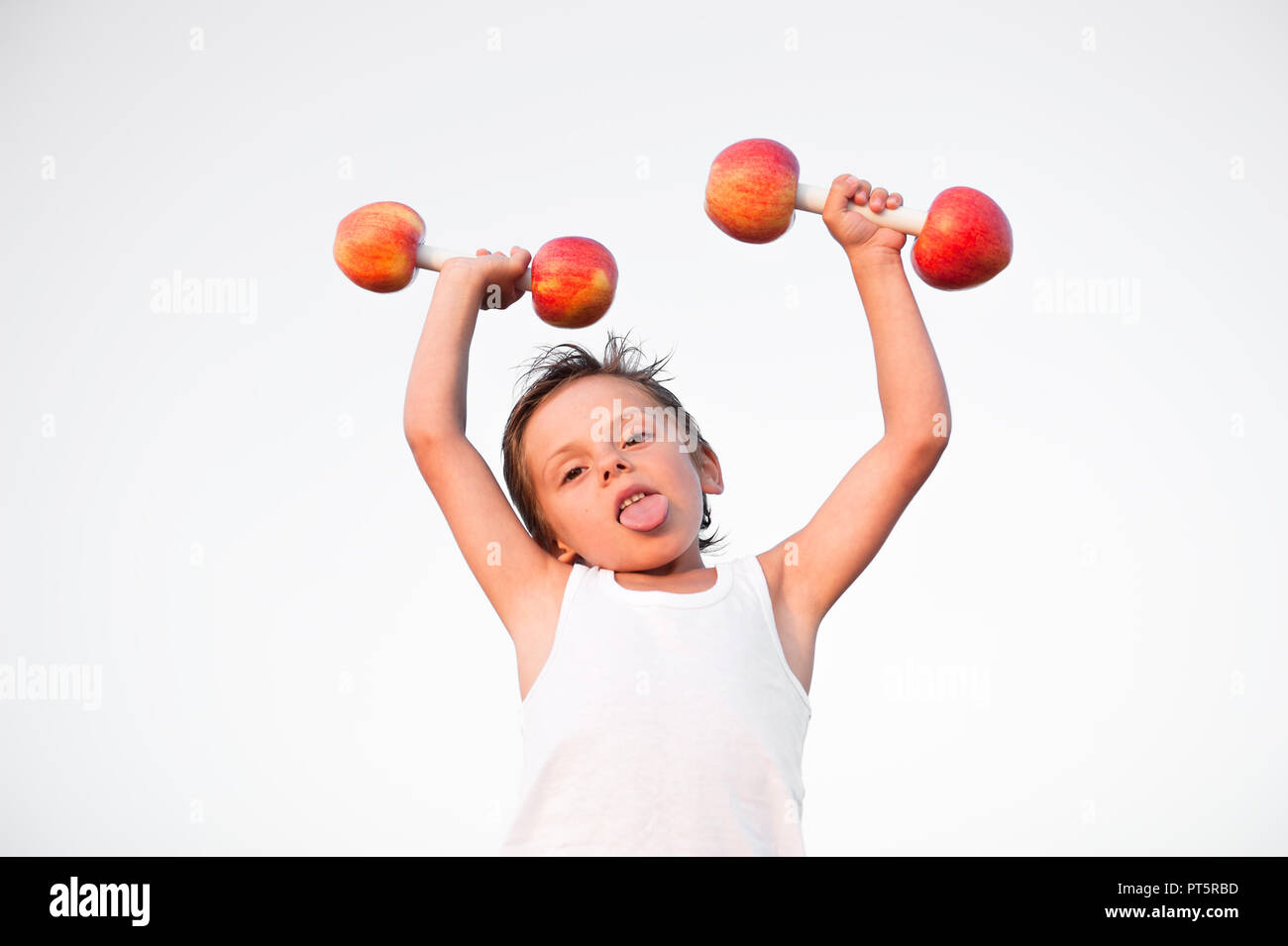 Starke gesunde süße kaukasischen Kind in weißem Hemd Hanteln aus frischen Äpfeln gemacht Stockfoto