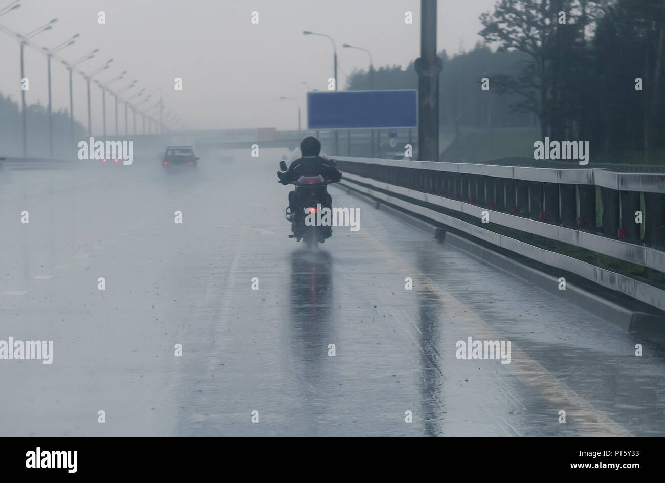 Der Motorradfahrer fährt auf dem Motorrad auf der Autobahn das Wetter zu regnerisch Stockfoto