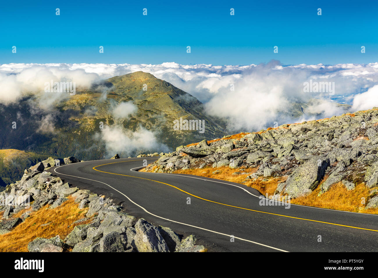 Kurvenreiche Straße in absteigender Reihenfolge von Mount Washington, NH an einem sonnigen Herbstnachmittag. Mount Jefferson Peak steht über eine dicke Schicht von Fluffy Clouds. Stockfoto