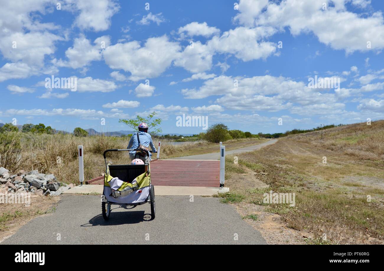 Frau auf einem Fahrrad mit einem Fahrradanhänger für Kinder, Townsville, QLD, Australien Stockfoto