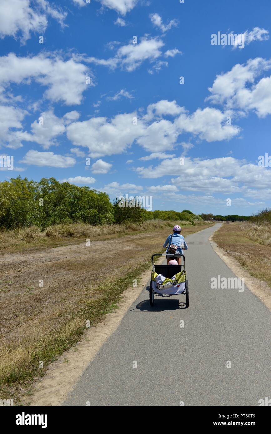 Frau auf einem Fahrrad mit einem Fahrradanhänger für Kinder, Townsville, QLD, Australien Stockfoto