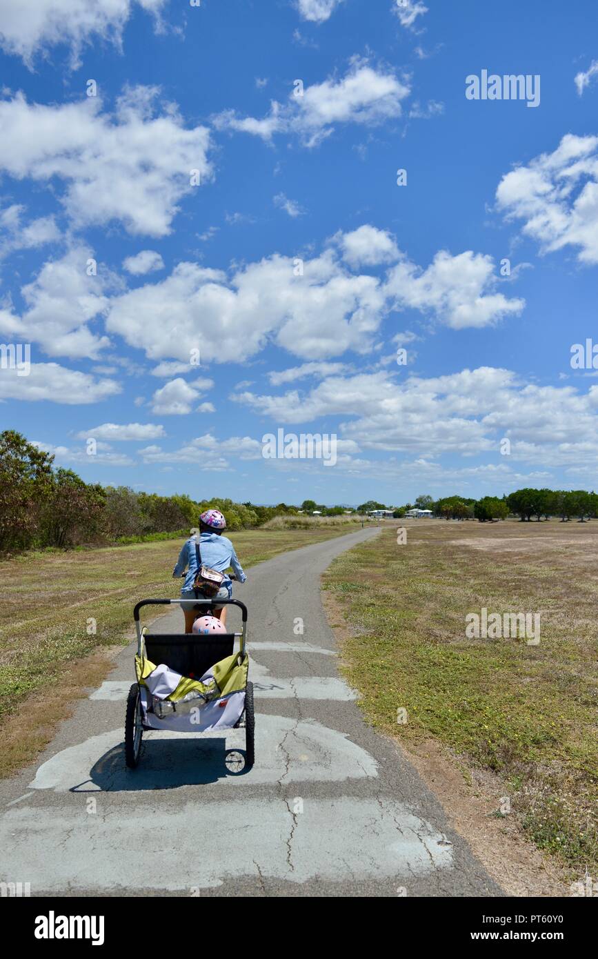 Frau auf einem Fahrrad mit einem Fahrradanhänger für Kinder, Townsville, QLD, Australien Stockfoto