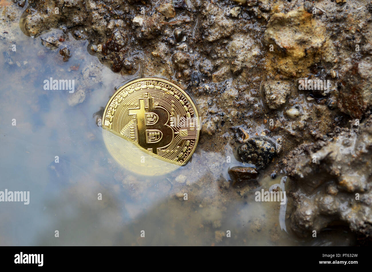 Kryptowährung sinkende Bitcoin im Schlamm Stockfoto