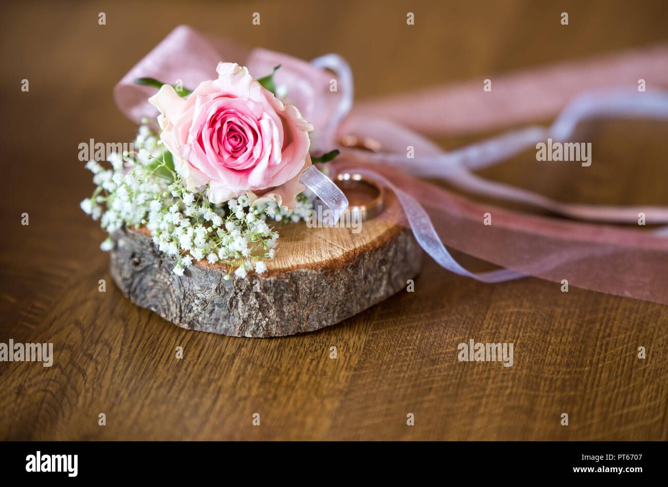 Hintergrund für den Herbst hochzeit einladung, zwei Hochzeit Ringe auf einem Stück Holz mit Rose Blume und Bänder, Platz für Text eingerichtet Stockfoto