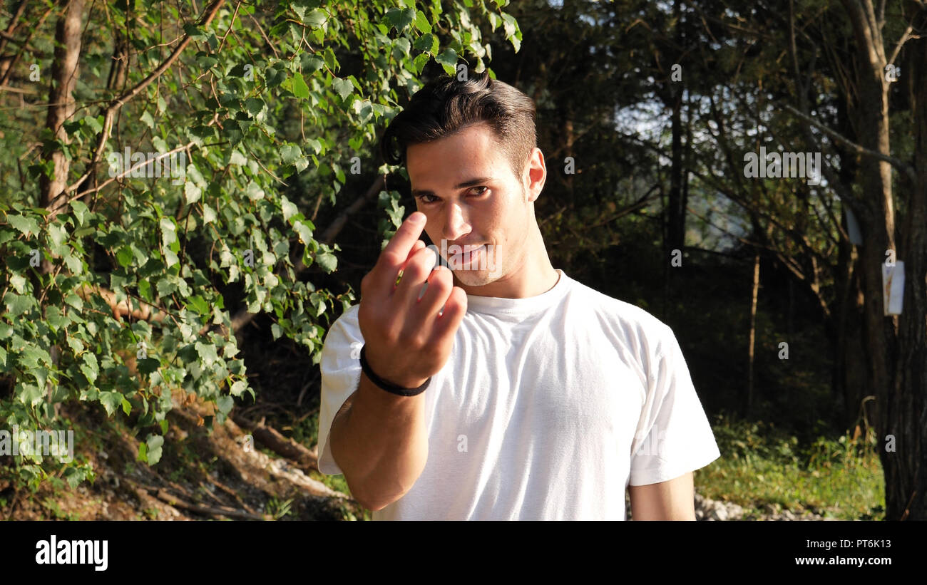 Junge Mann in der Natur bei Anrufen, die näher mit Geste Stockfoto