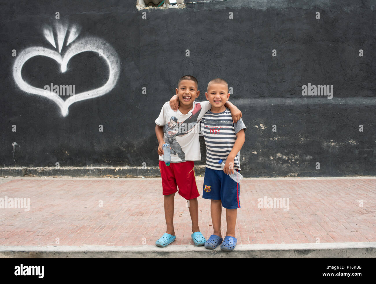 Zwei fröhliche Jungs umarmen sich freundlich mit einem großen Lächeln und leeren Plastikflaschen in den Händen. Santa Marta, Kolumbien. September 2018 Stockfoto