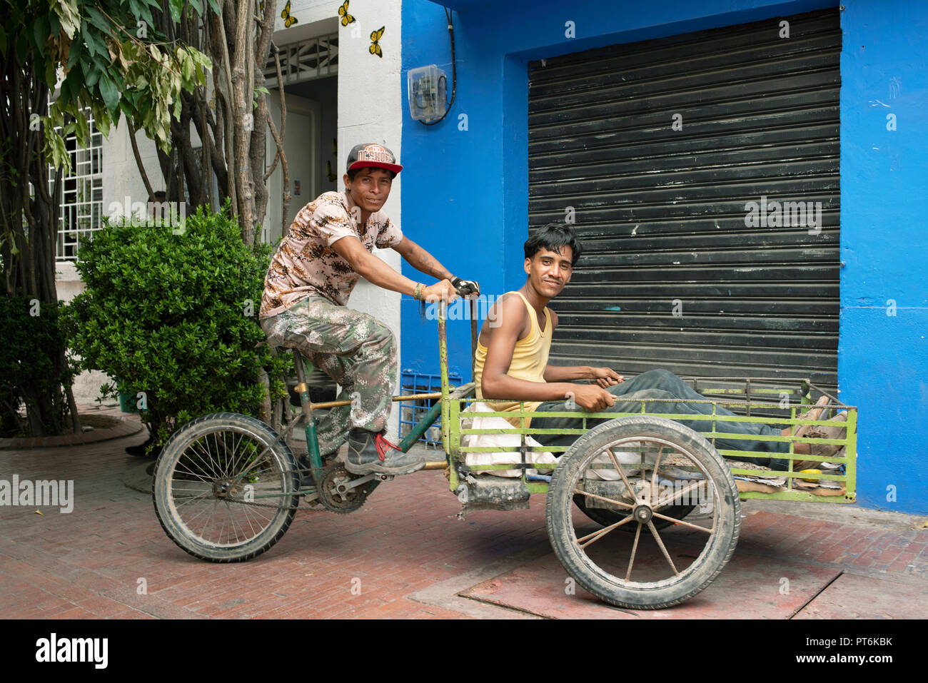 Porträt von zwei jungen Latino-Männern, nach der Arbeit, sitzen in einem Lastenrad. Santa Marta, Kolumbien. Umweltportrait, redaktionelle Verwendung. September 2018 Stockfoto