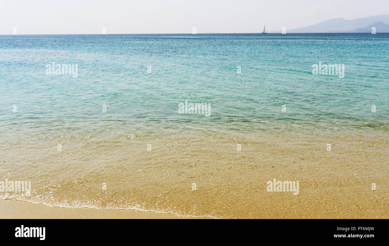 Eine Segelyacht gegen einen ruhigen türkisfarbenen Meer mit Sonnenlicht durchflutet. Ein blauer wolkenloser Himmel an einem hellen Sommertag. Tropische Landschaft Stockfoto