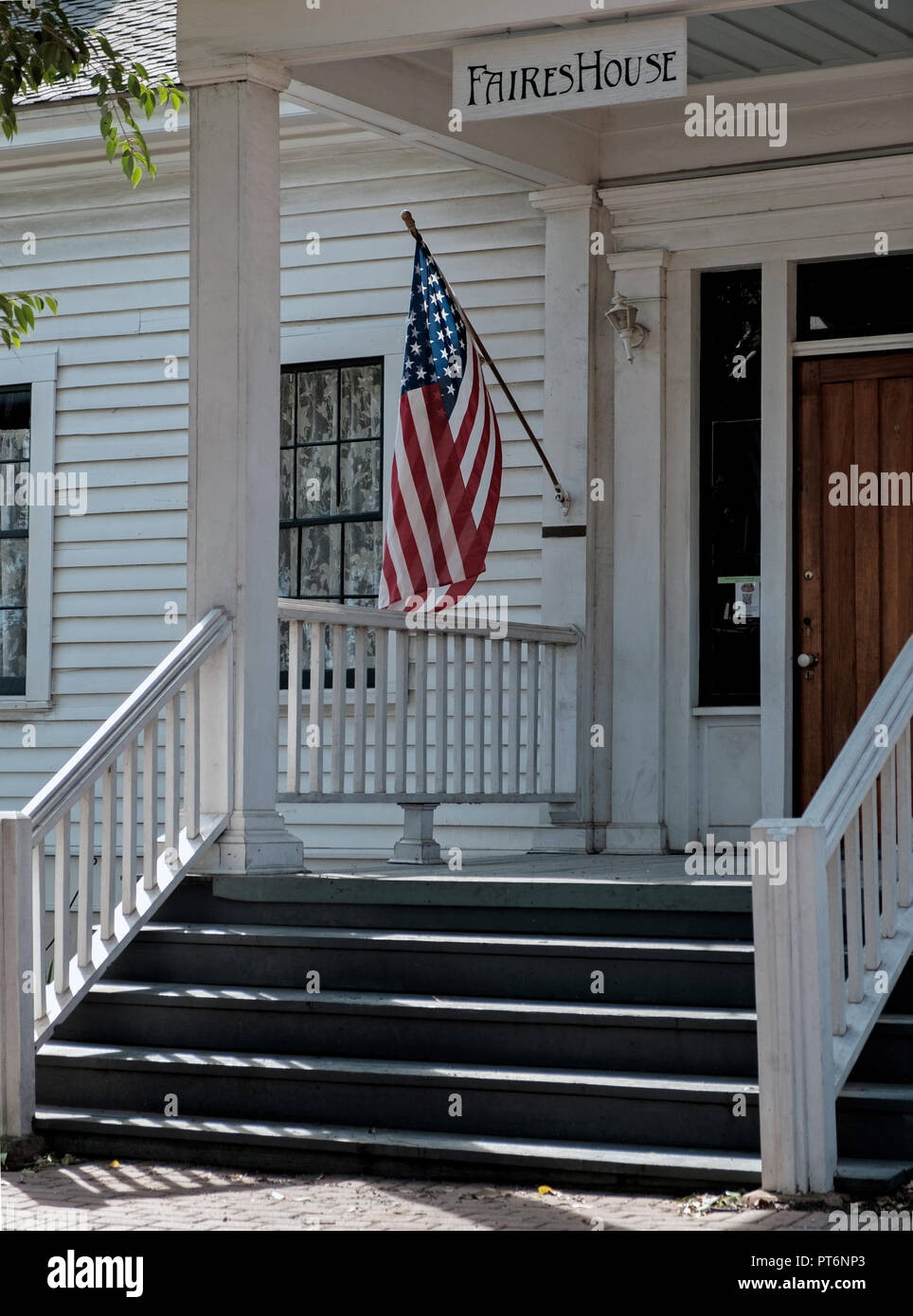 Vor dem Eingang des alten, weiß geschuppt Haus mit Stufen. Build 1854. Amerikanische Flagge auf erweiterten Pol. Messe Haus, Kastanie Square, Mckinney Texas. Stockfoto
