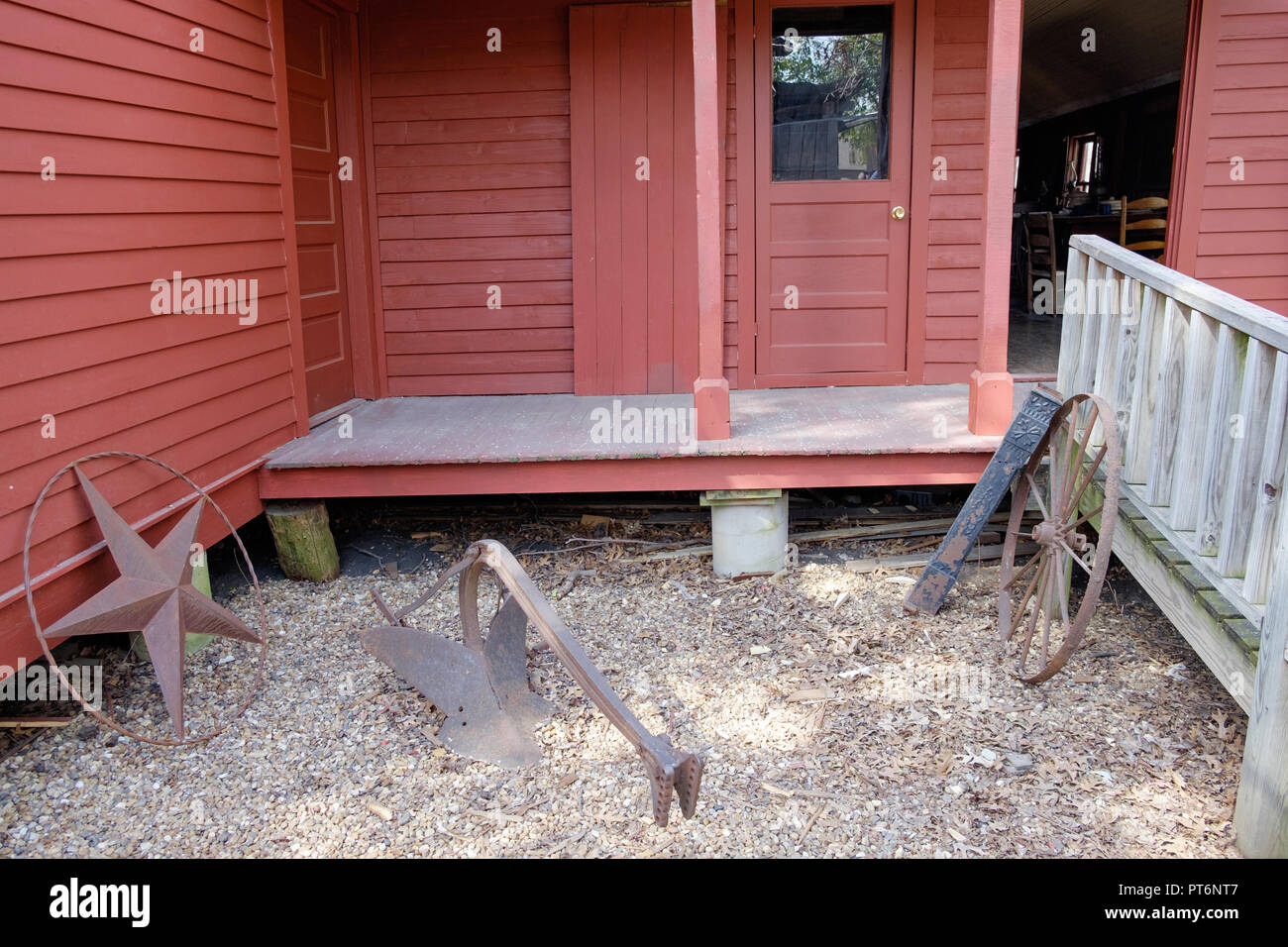 Zurück von alten, roten Holzhaus. Two-Bit Taylor Inn mit Eisen Texas Stern, & alte Wagenrad. Tür öffnen. Chestnut Square Historic Village, McKinney Texas. Stockfoto