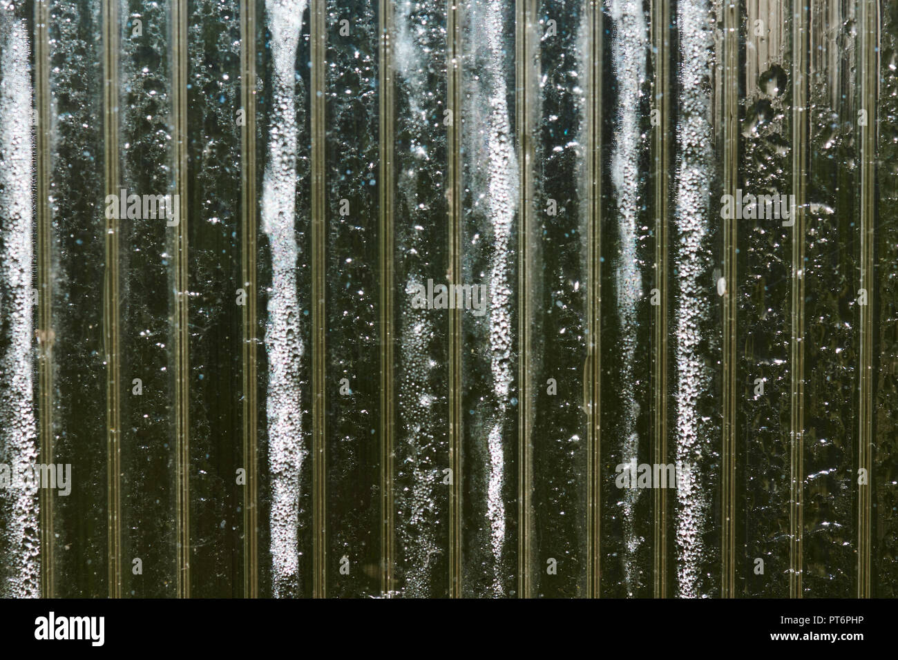 Schöne Textur beschlagene Glas, in Abschnitte unterteilt und Wassertropfen. Vertikale Linien aufteilen Hintergrund in Teile. Unter den rosa Streifen Stockfoto