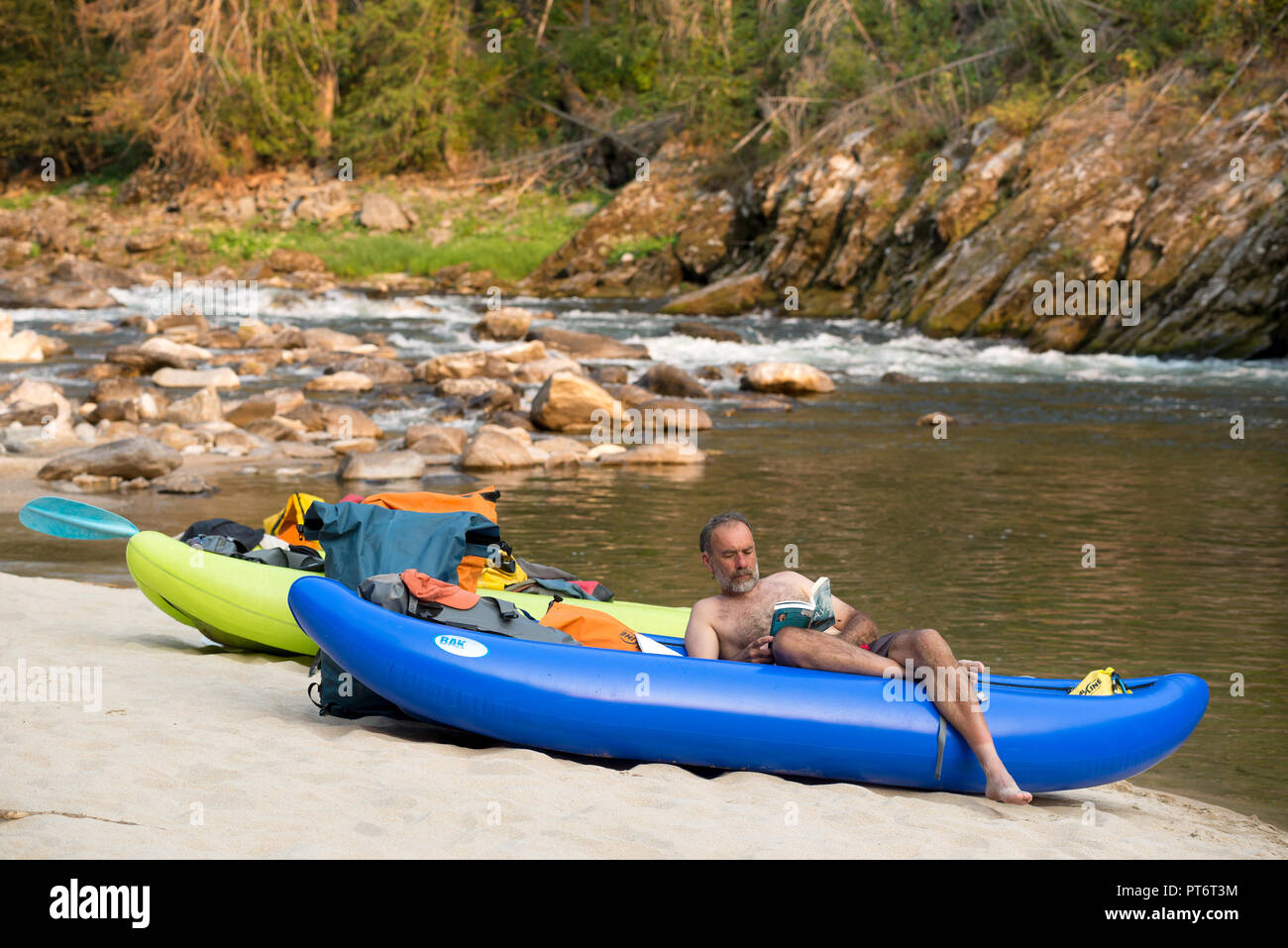 River runner Lesen und Entspannen in einem aufblasbaren Kajaks am Strand entlang der Idaho Selway River. Stockfoto