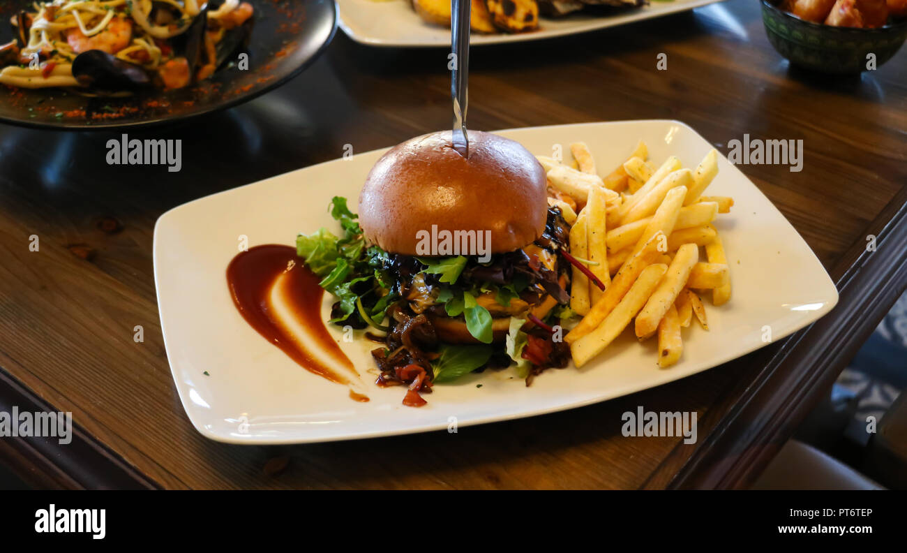 Fast food Konzept. Hamburger mit Pommes frites auf weißem Teller. Nahaufnahme, blur Hintergrund. Stockfoto