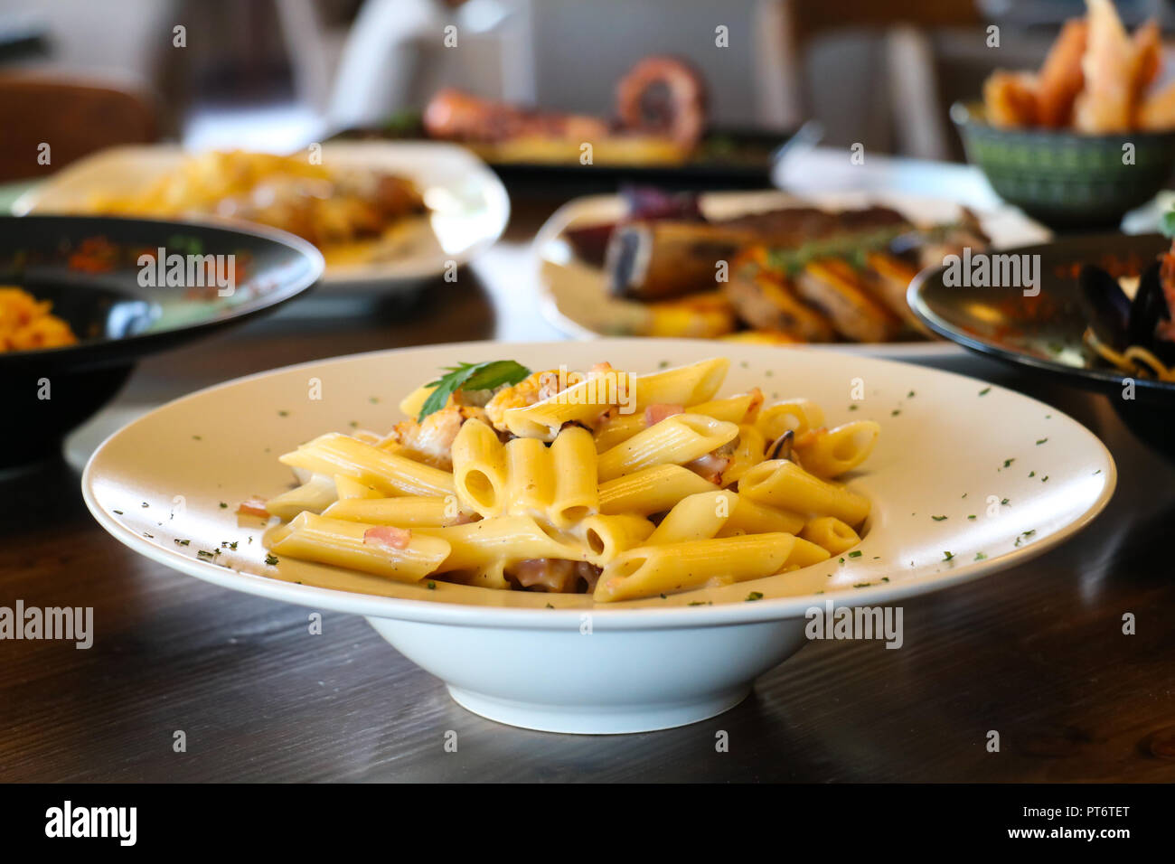Essen Konzept. Pasta Penne mit Pilzen, Speck und Schlagsahne auf weiße Platte. Blur Platten mit Lebensmittel Hintergrund. Stockfoto